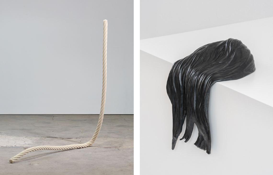 Grey cloudy forms billow from the top of two glass panels leaned against a wall