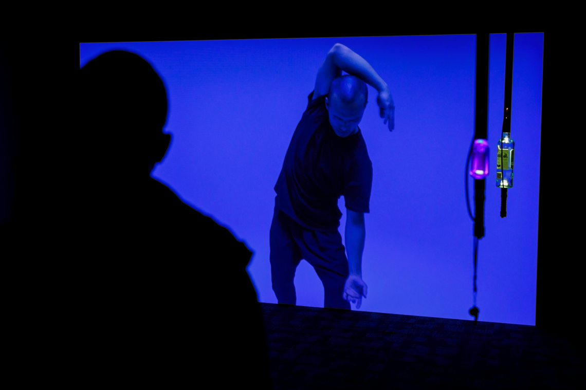 Dark room with blue colored film and hanging lit bottles