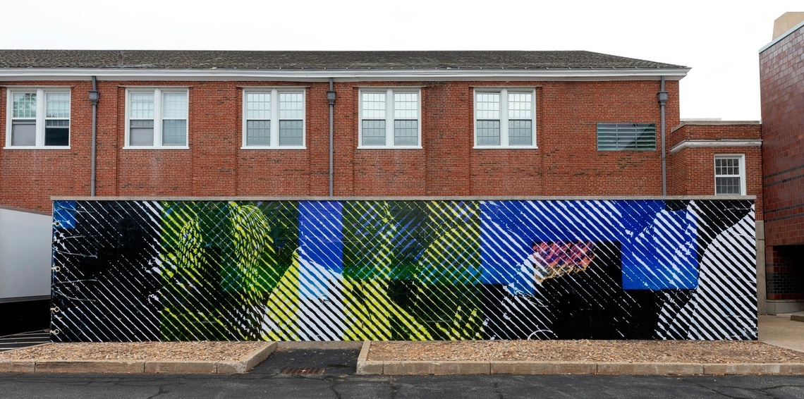 Large cool-toned halftone mural in a parking lot in front of a brick building