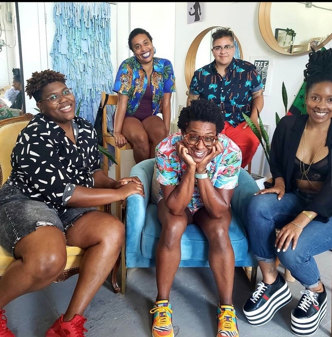 Five seated people with various colorful shirts pose and smile for a photo