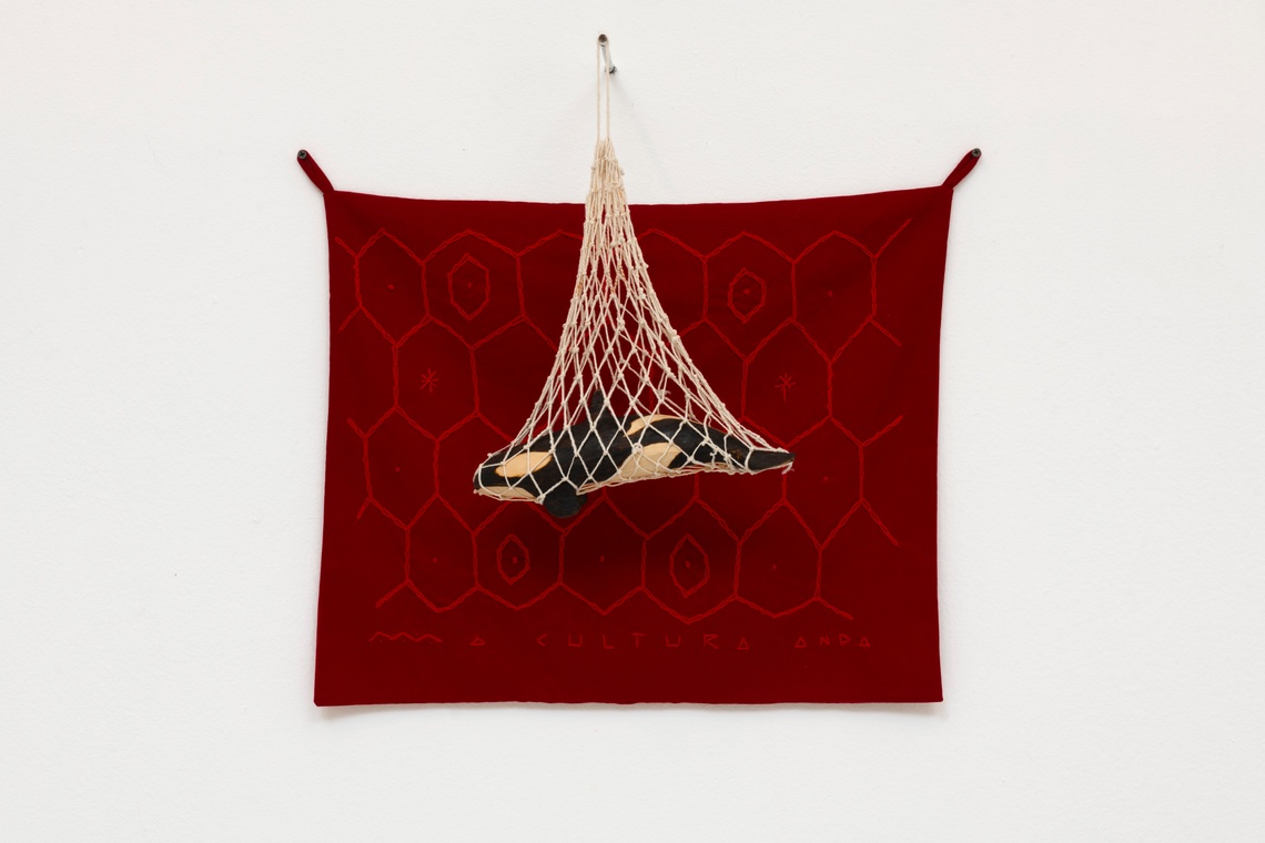 dark red textile with small orca enclosed in cream netting